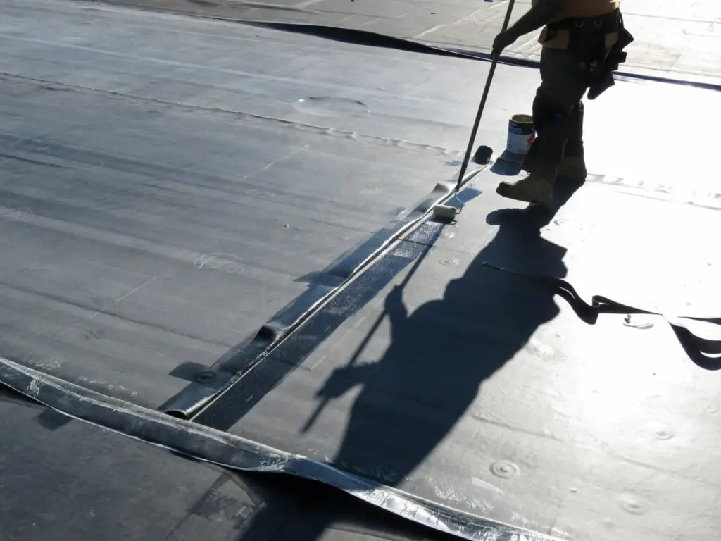 Applying roofing adhesive (EPDM bonding adhesive) to an EPDM field seam.