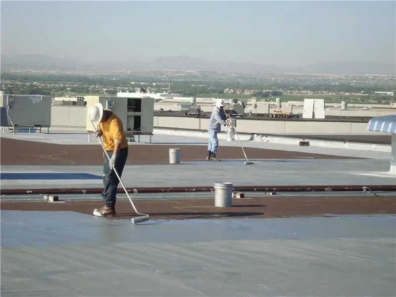 Applying an aluminized roof coating to a new smooth-surfaced asphalt built-up roof.