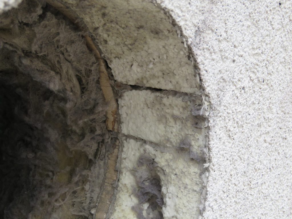An exhaust duct hole through the EIFS cladding reveals the constituent EIFS components.