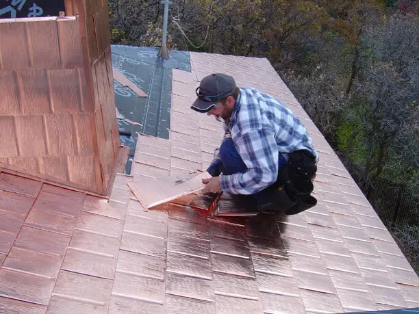 a roofer installing copper roof shingles.