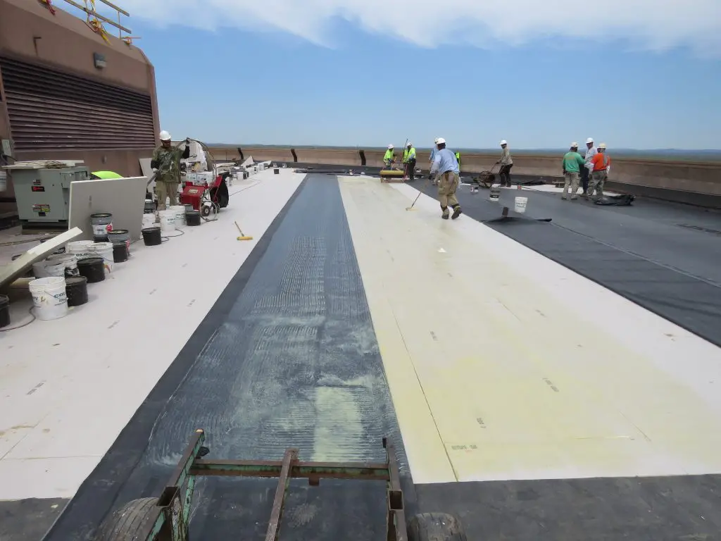 Applying membrane adhesive to the cover board in a fully-adhered EPDM system.