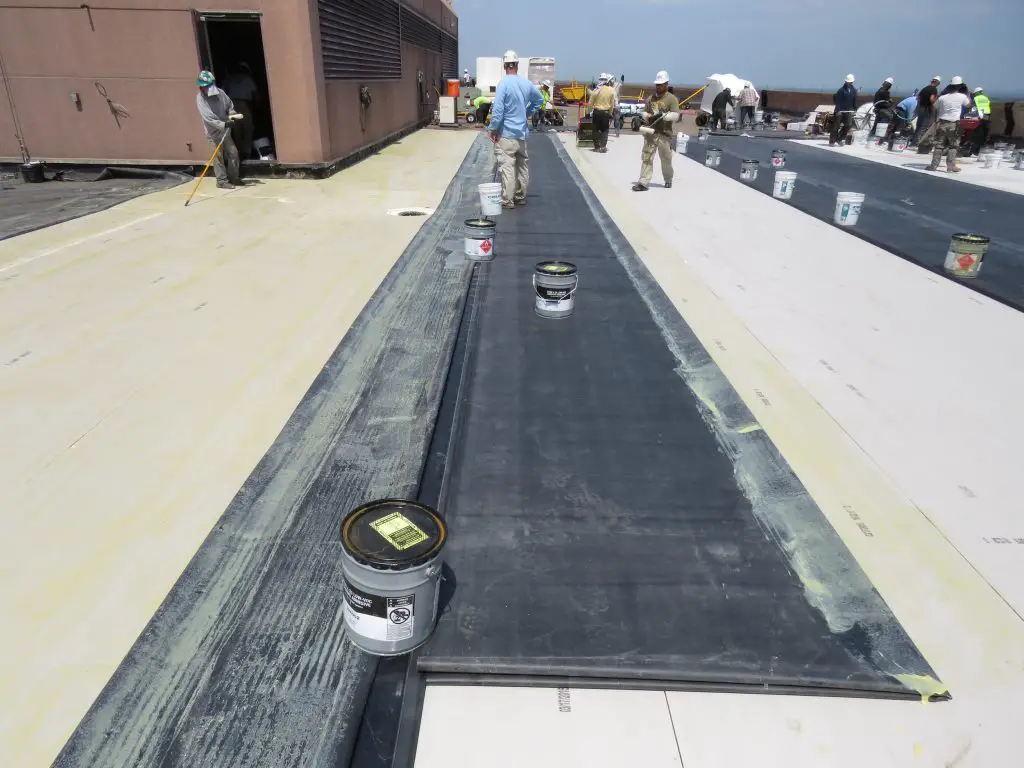 Membrane adhesive is applied both to the substrate (the cover board) and the EPDM membrane itself.