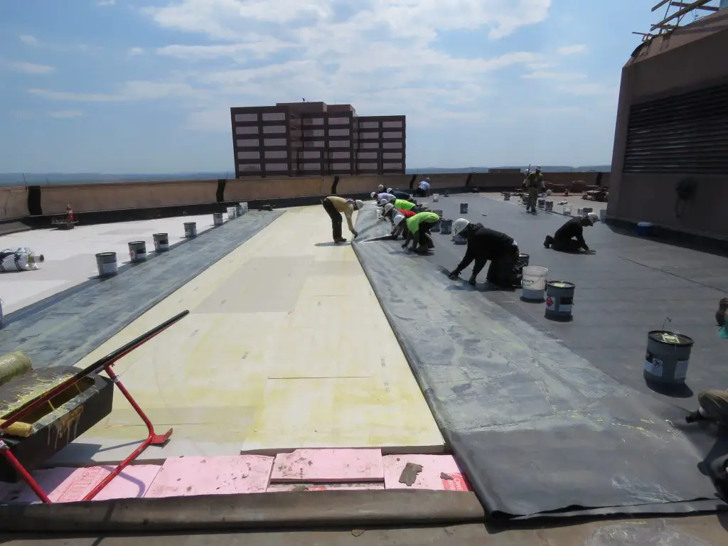 Carefully rolling the EPDM membrane into place.