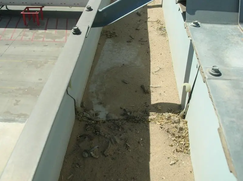 A roof gutter that has filled up about a quarter of the way with wind-blown dirt