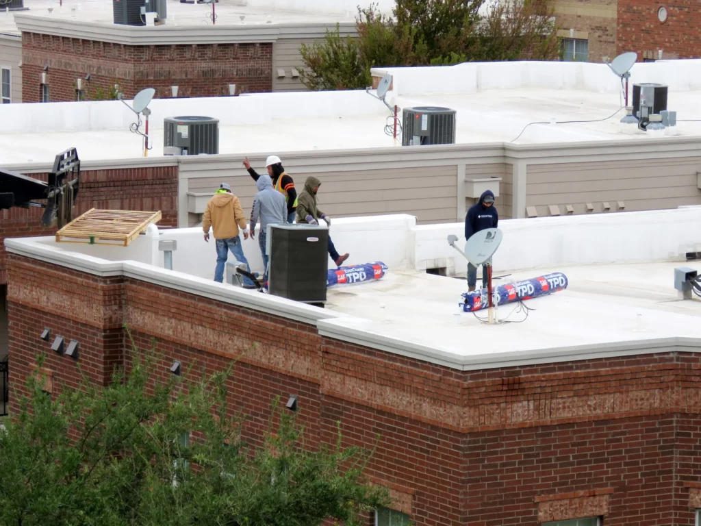 Loading new rolls of TPO roof membrane onto an old TPO roof .