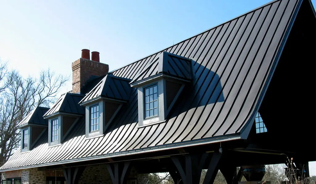 A brown standing seam metal roof (image with four small dormers.