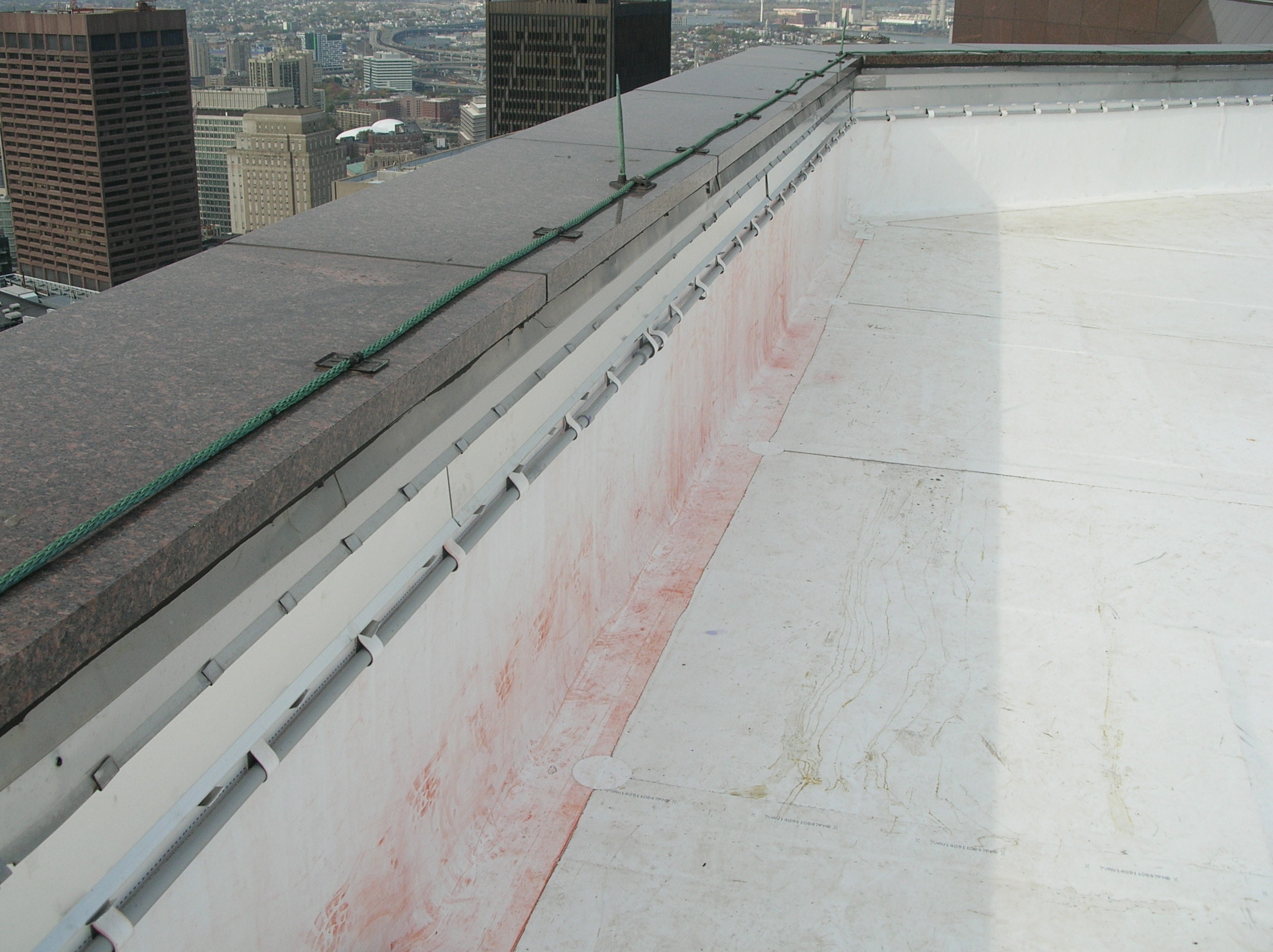 Natural stone (polished granite) coping with lightning protection system on a skyscraper roof parapet wall.