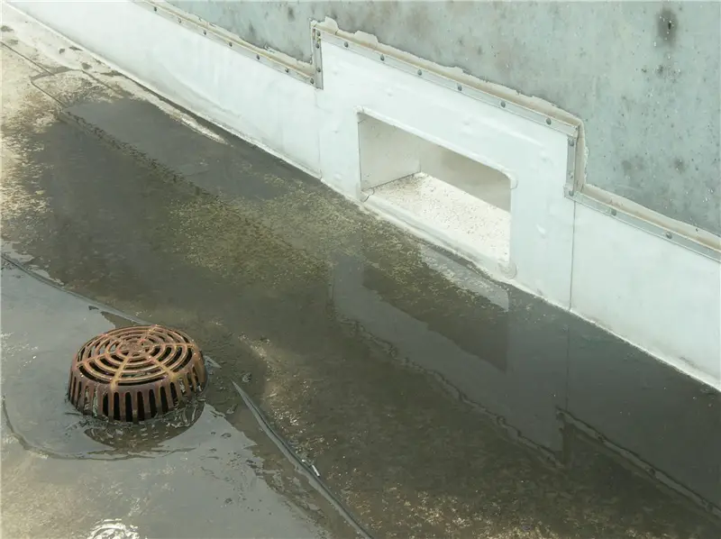 A thru-wall overflow scupper near a drain on a TPO roof.