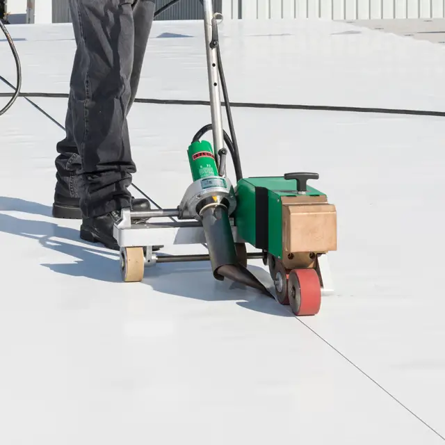 Heat-welding the seam that joins two sheets of PVC roof membrane,