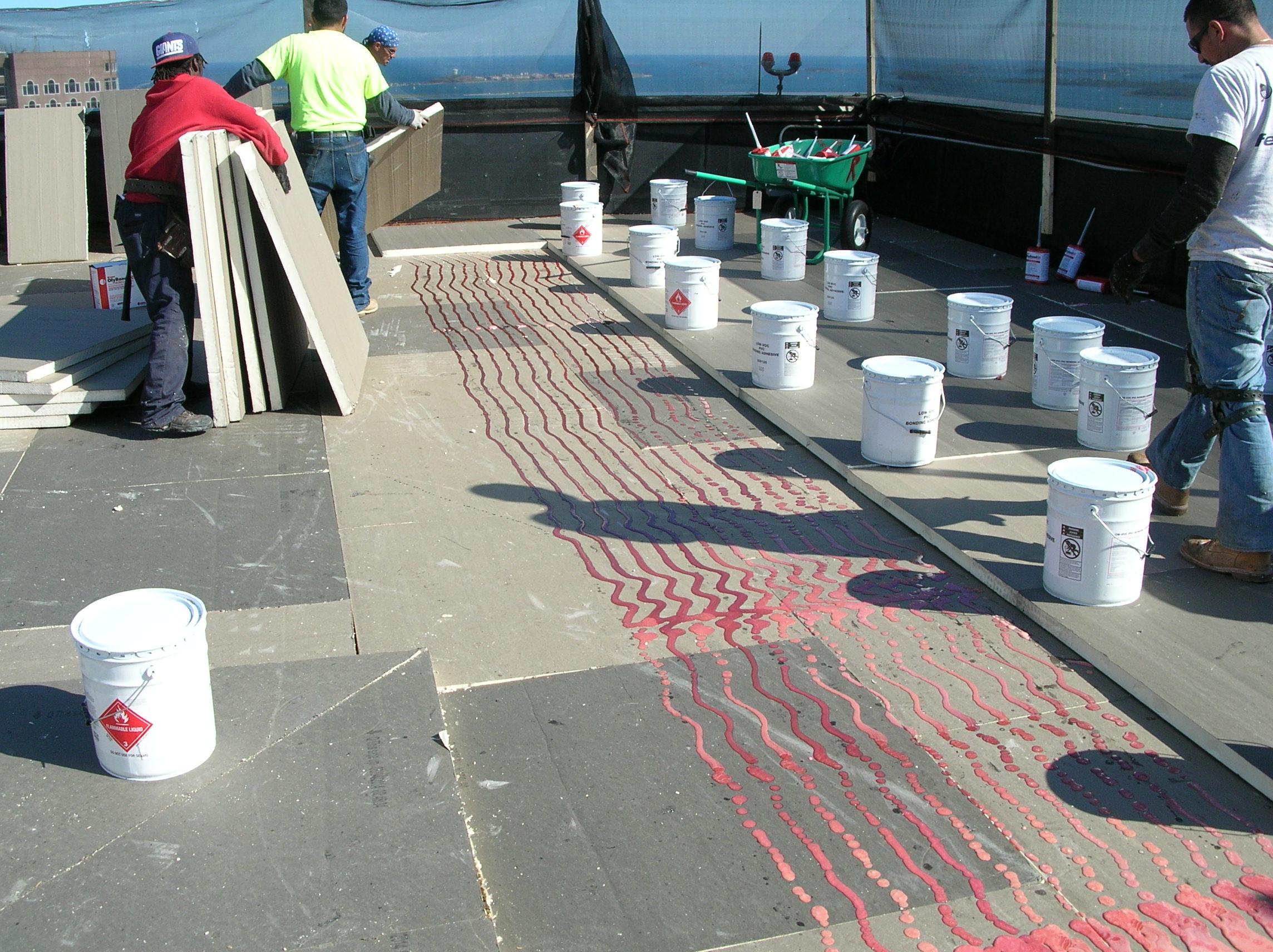 Installing polyisocyanurate insulation boards in adhesive during a roof installation.