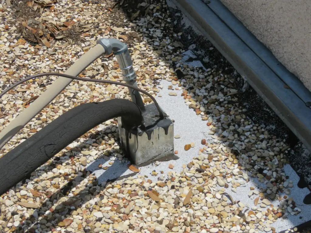 Galvanized steel pitch pocket on a built-up roof with various conduit penetrations.