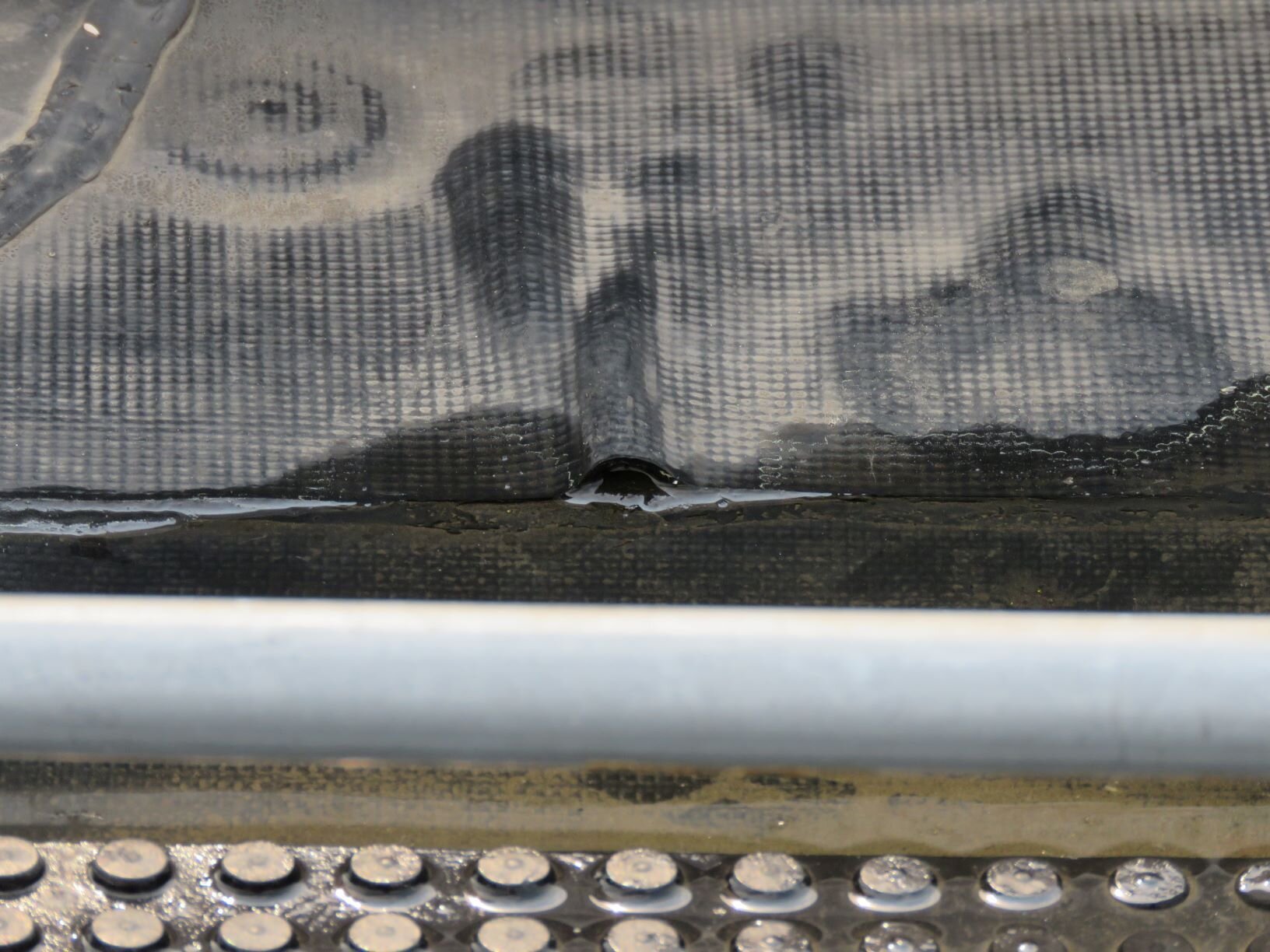 Reinforced EPDM showing reinforcing scrim pattern at a fishmouth.