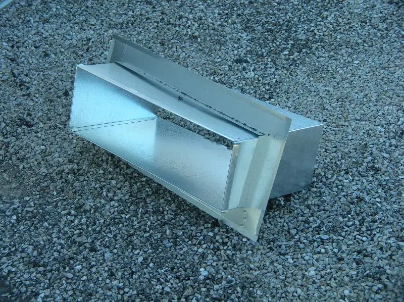 A sheet metal scupper box ready for installation sitting on a roof.