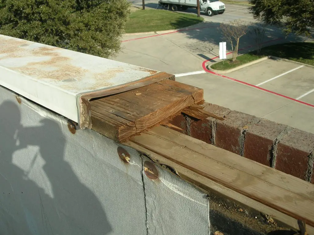 Metal coping, or cap flashing, being removed from a parapet wall.
