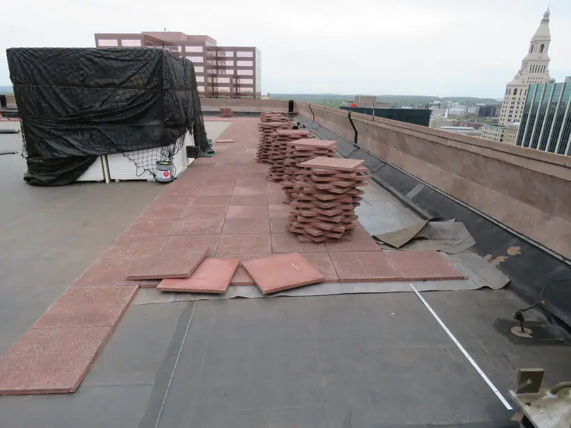 These brick-colored concrete pavers weigh about 12 pounds per inch per square foot. They are being installed as ballast on an EPDM roof.