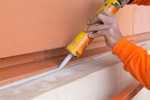 Applying NP1 urethane sealant at a building joint.