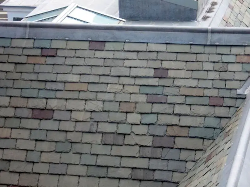 A five-year-old slate roof with a blend of colors. Damaged slates are the result of carelessness by workers accessing the roof after the installation.