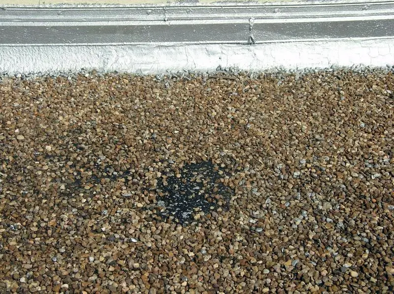 Roof blisters in built-up roofs can be identified by spots with missing gravel like this.