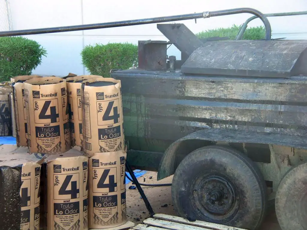 Kegs of Type 4 roofing asphalt next to an asphalt kettle.