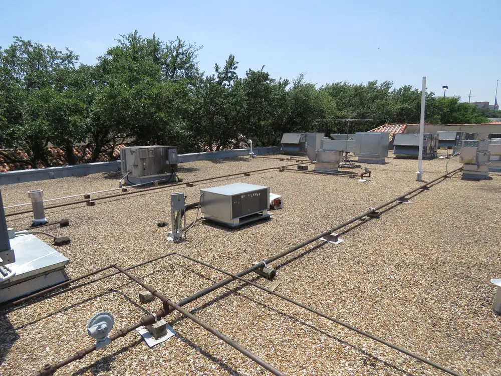 Gravel-surfaced asphalt built-up roof with a lot of rooftop equipment on it.