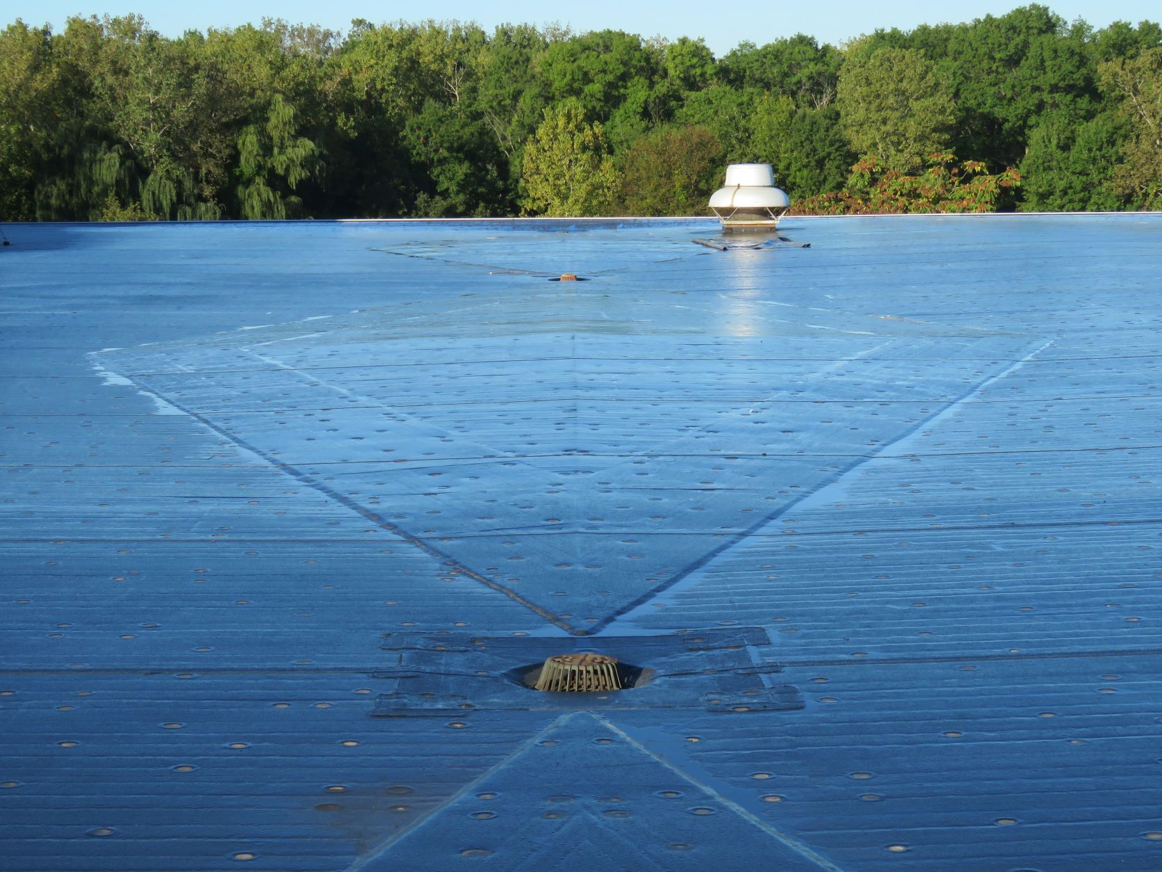 A fully-adhered EPDM roof with roof crickets and drains.