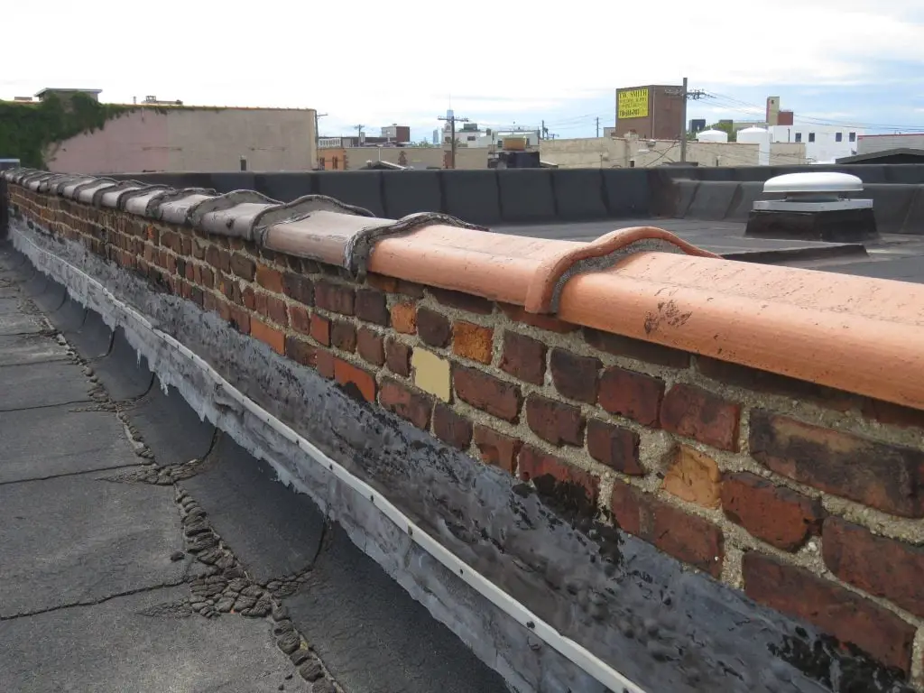 Camelback terra-cotta coping on a brick wall.