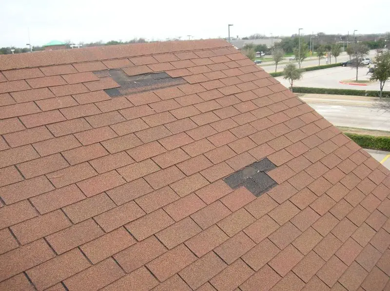 Wind-damaged 3-tab asphalt shingle roof.