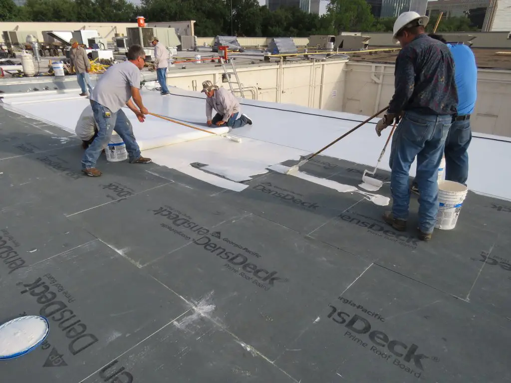 Applying membrane adhesive for a fully-adhered PVC membrane.