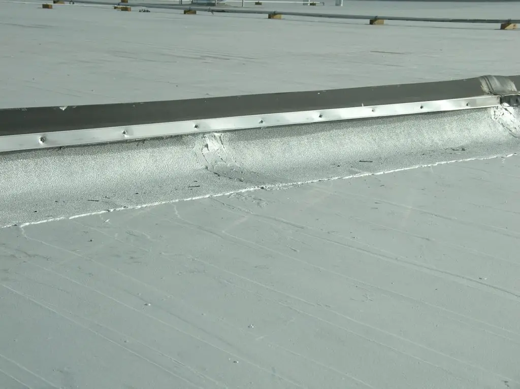 A curbed expansion joint between two roof sections on a smooth-surfaced built-up roof.